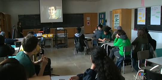 Students wearing green shirt and watching a movie in a class