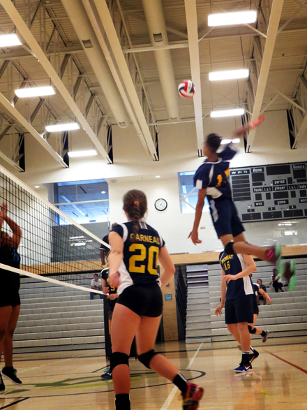 A boy from Sir Oliver Mowat soars above his teammates to spike the ball down against his opponents.