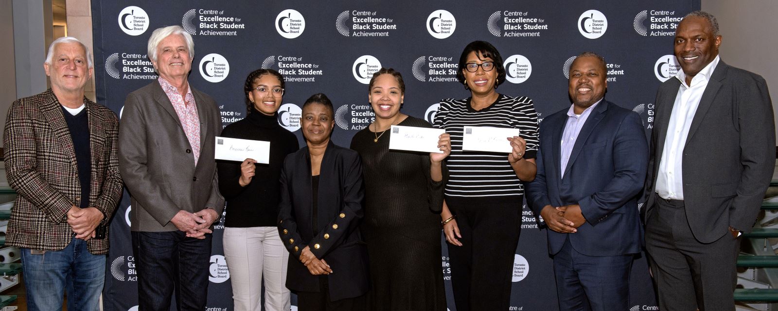  Administrators from the TDSB stand with award winners who are holding cheques, alongside members of the selection committee and donors.
