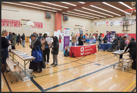 A wide shot of many people visiting various booths in a gym at TDSB's Pathways to Adulthood for Students with Disabilities' Transition Fair.