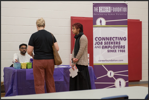 A family receiving information from The Career Foundation booth at TDSB's Planning for adulthood for students with disabilities transition fair