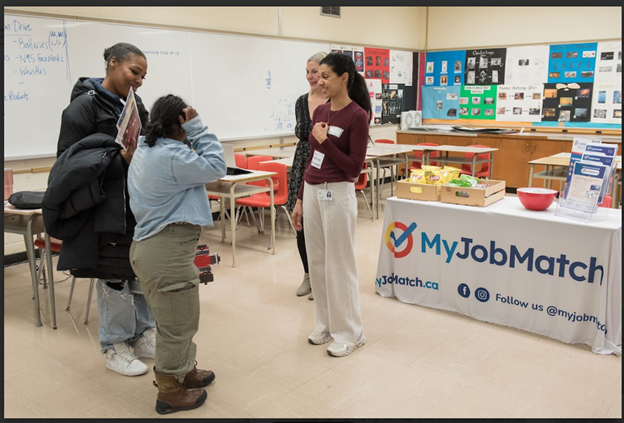 Four people standing in a room where myJobMatch hosted interactive activities supporting resume writing at TDSB's planning for adulthood for students with disabilities transition fair