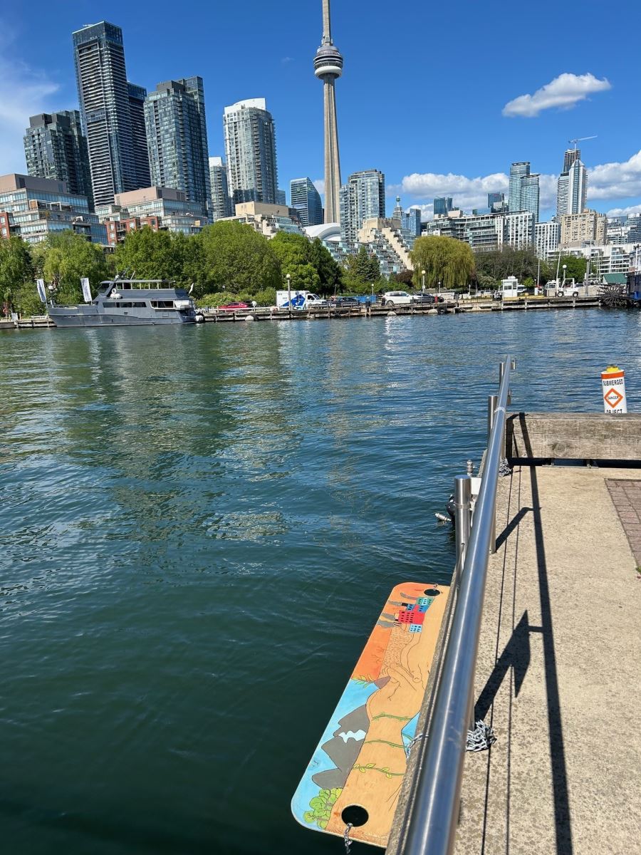 A view of the Toronto skyline from the waterfront with a colorfully painted duckling dock sitting in the water