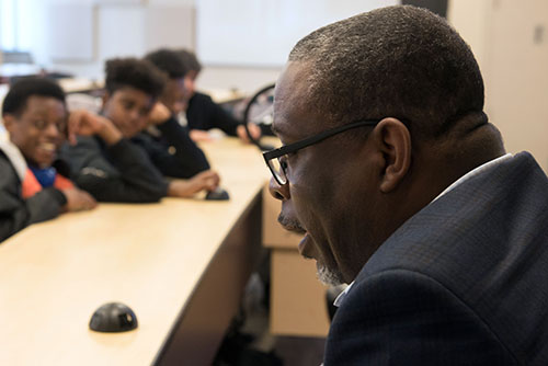 A mentor speaks as three young Black students look on at the Stand Up Conference