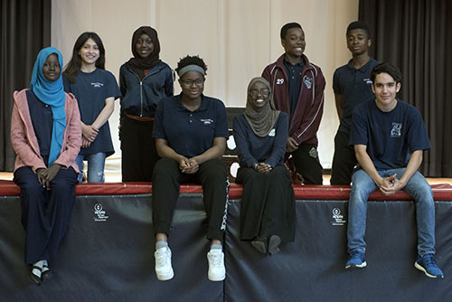 A diverse group of students sits on the school’s stage.
