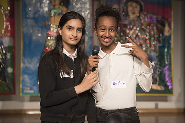 two students stand with a microphone on stage and participate in the VIBE Conference