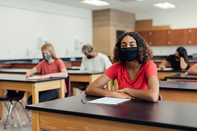 Young students wear masks inside their classroom while doing school work