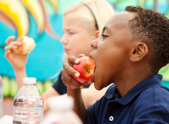 A child taking a big bite out of an apple