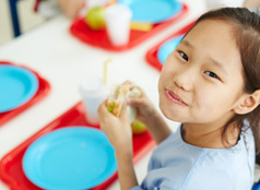 A smiling child enjoying a sandwich