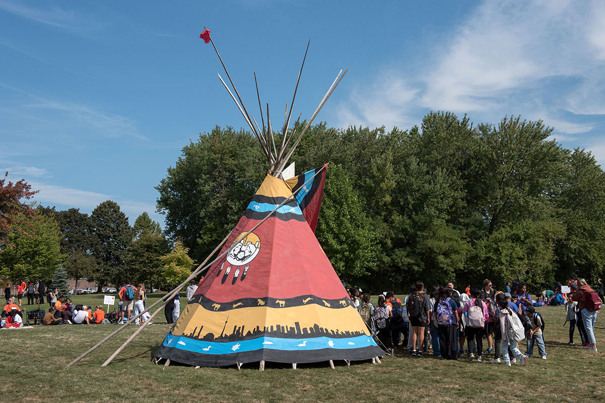 Colourful tipi in field with attendees surrounding