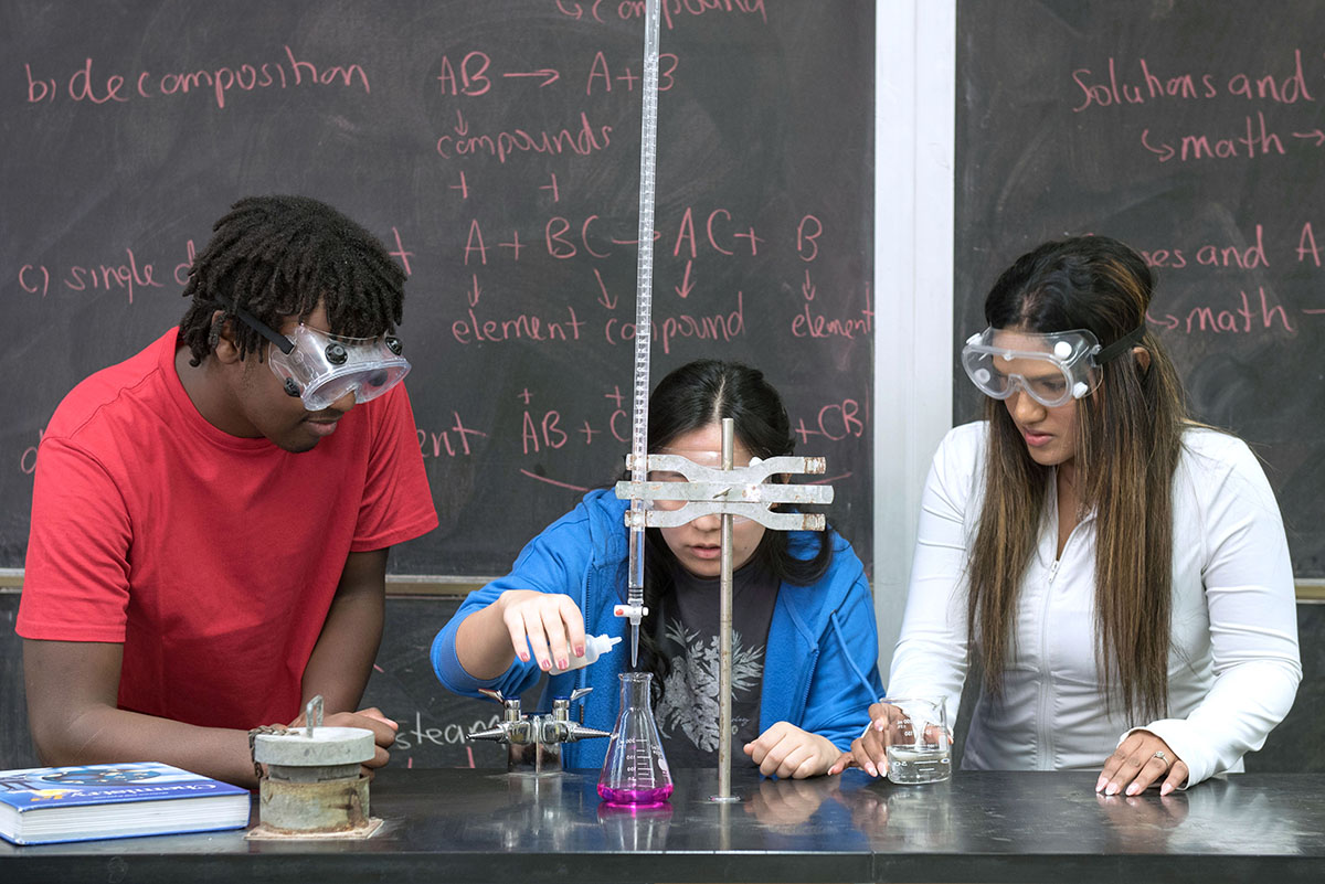 Three students performing a science experiment