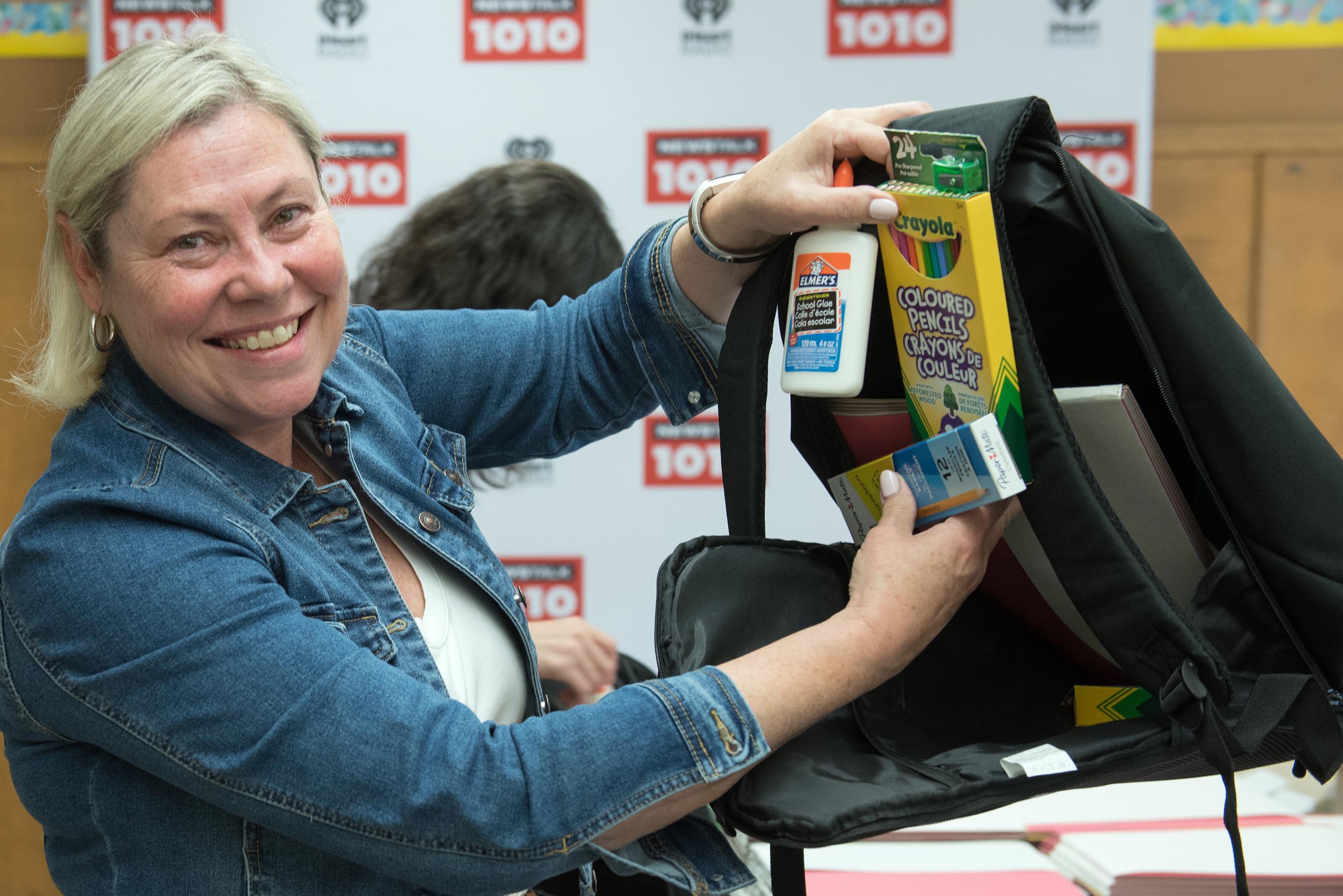 Staff member holding up backpack and school supplies