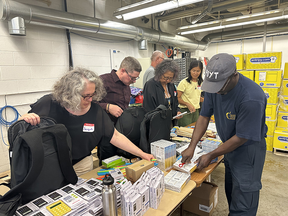 Staff standing and working to place supplies in backpacks