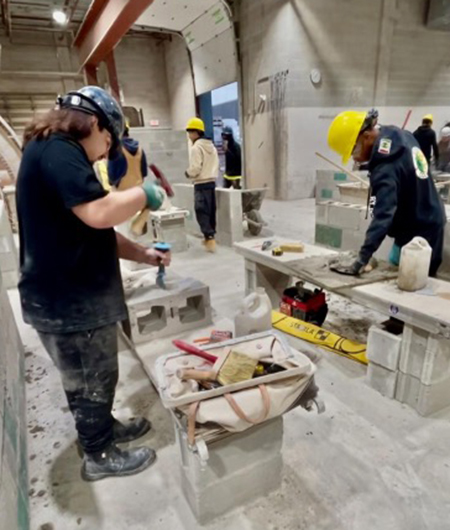 Two students in safety gear working on stone construction
