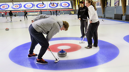 A set of three coed competitor students playing curling at Toronto Cricket Skating & Carling Club
